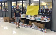 TCCHS sophomore Kaleb Ward stands in front of a pile of collected relief supplies.
