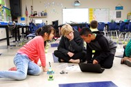 Dr. Caitlin Dooley (center), Georgia Department of Education Deputy Superintendent of Teaching and Learning, observes fourth graders Haley Gonzalez, from left, and Enrique Lopez as they program robots in the coding classroom at Cross Creek Elementary.